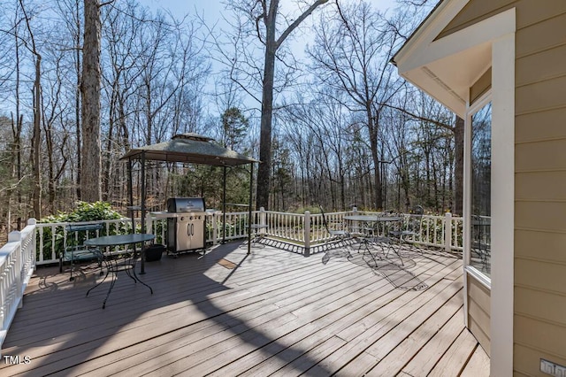 wooden deck with outdoor dining space, a gazebo, and area for grilling