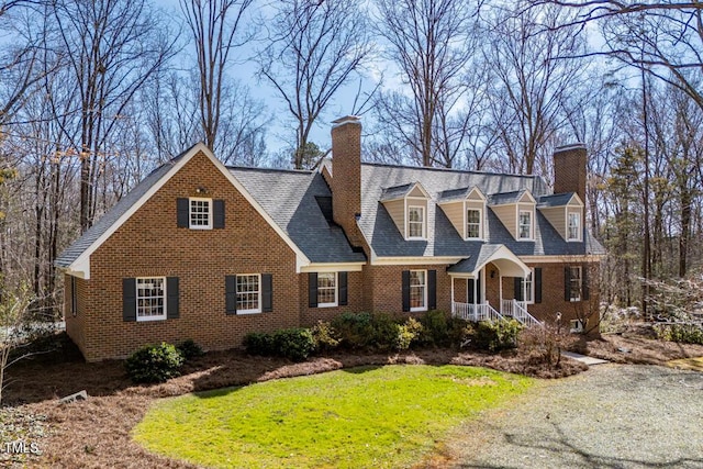 cape cod home featuring a front lawn, brick siding, and a chimney