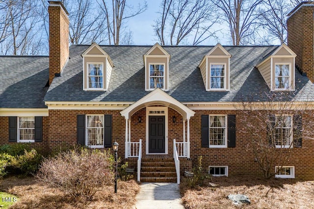 cape cod house featuring brick siding and a shingled roof