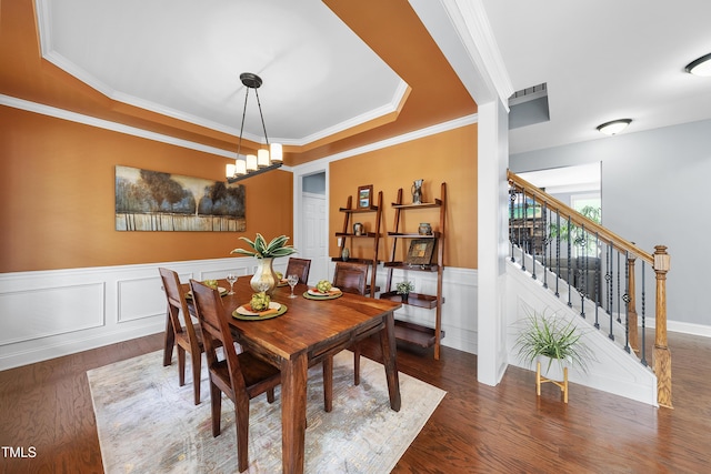 dining area with stairway, a wainscoted wall, wood finished floors, crown molding, and a tray ceiling
