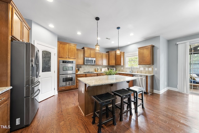 kitchen featuring stainless steel appliances, dark wood-style floors, tasteful backsplash, a kitchen island, and brown cabinets