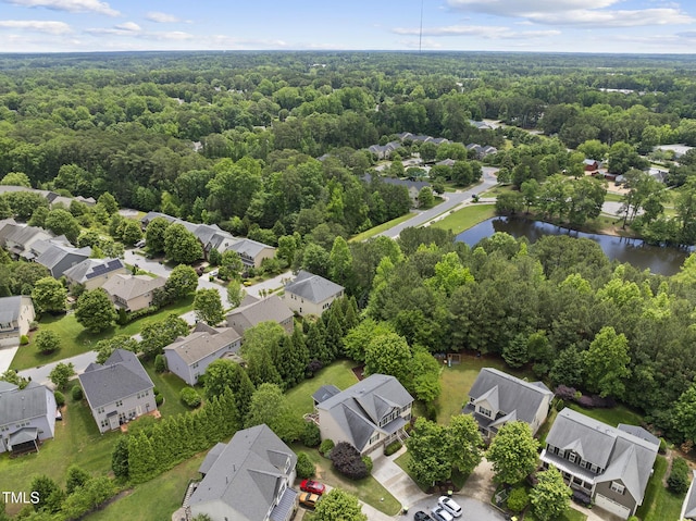 aerial view of residential area with a large body of water and a heavily wooded area