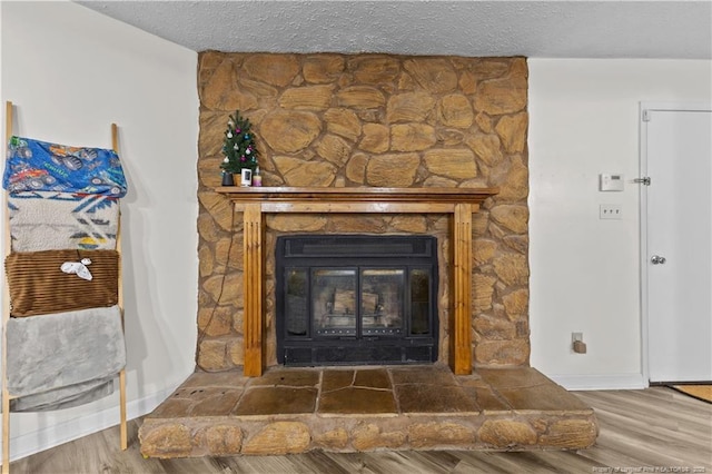 details with a stone fireplace, wood finished floors, and a textured ceiling