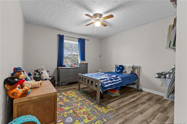 bedroom with a ceiling fan, baseboards, light wood finished floors, and a textured ceiling