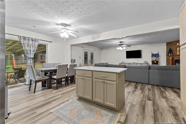 kitchen featuring light wood-type flooring, gray cabinetry, ceiling fan with notable chandelier, a textured ceiling, and a kitchen island