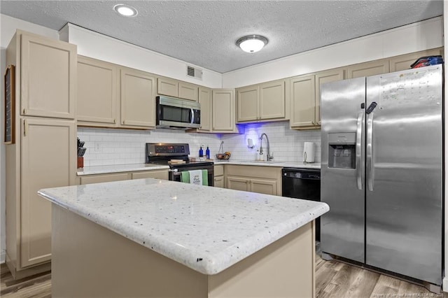 kitchen with visible vents, light wood-style flooring, stainless steel appliances, and a sink