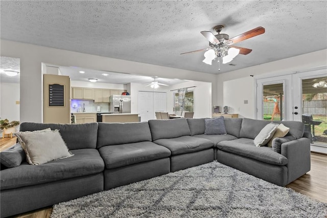 living room featuring french doors, a textured ceiling, ceiling fan, and wood finished floors