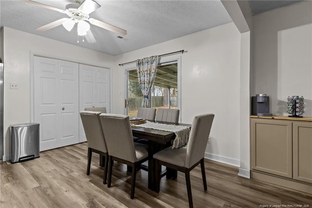 dining space with baseboards, a textured ceiling, ceiling fan, and wood finished floors