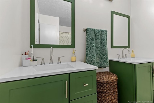 full bath with a sink, a textured ceiling, and two vanities