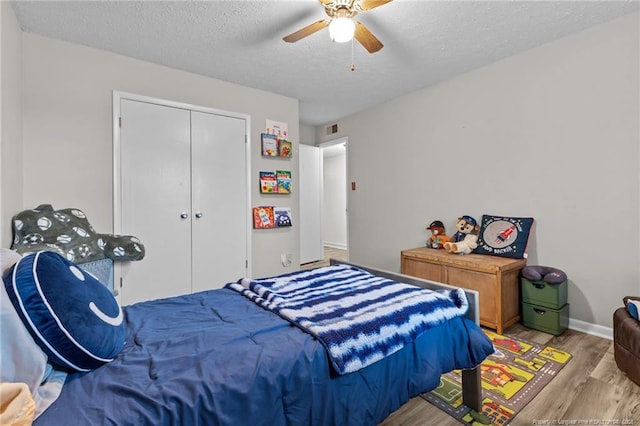 bedroom featuring visible vents, a textured ceiling, wood finished floors, a closet, and ceiling fan