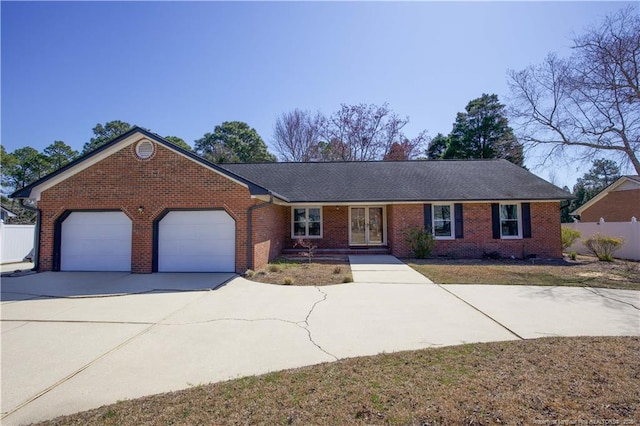 ranch-style home with brick siding, driveway, an attached garage, and fence