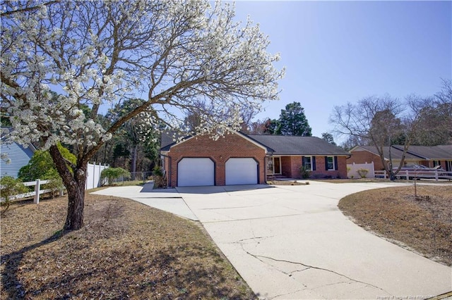 ranch-style home featuring a garage, fence, brick siding, and driveway