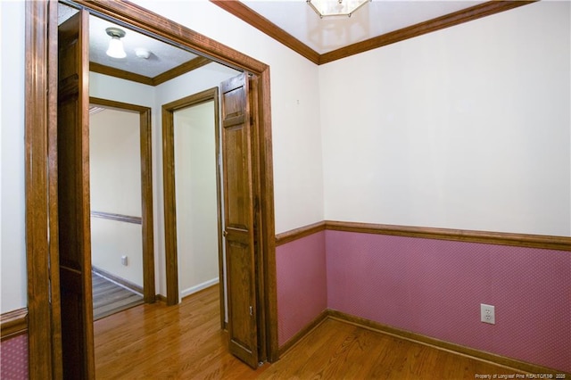 interior space with baseboards, wood finished floors, and crown molding