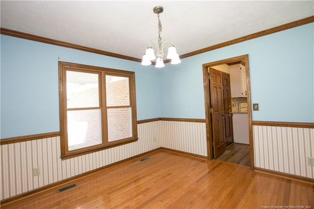 spare room featuring a notable chandelier, wainscoting, visible vents, and wood finished floors