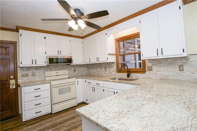 kitchen featuring ornamental molding, a sink, stainless steel microwave, white electric range oven, and white cabinetry