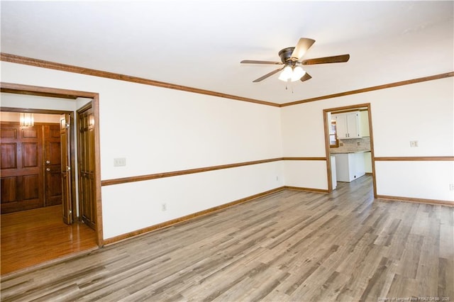 empty room featuring a ceiling fan, light wood-style floors, baseboards, and ornamental molding