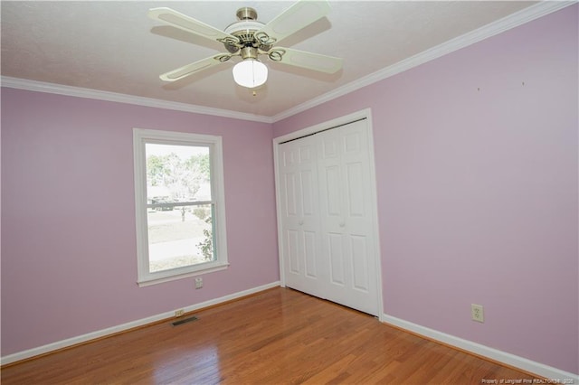 unfurnished bedroom featuring visible vents, baseboards, light wood-style floors, and crown molding