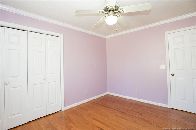 unfurnished bedroom featuring baseboards, ornamental molding, light wood-style flooring, a closet, and a ceiling fan