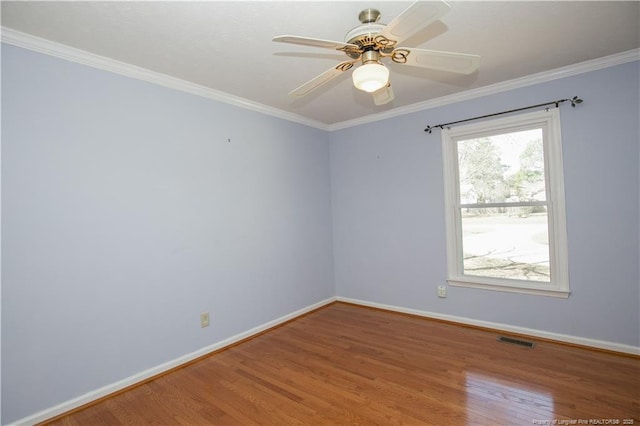 empty room featuring crown molding, wood finished floors, visible vents, and baseboards