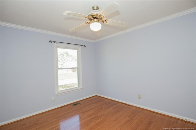 spare room featuring visible vents, baseboards, wood finished floors, and crown molding