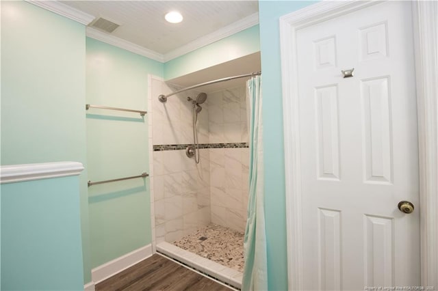 full bathroom featuring visible vents, wood finished floors, ornamental molding, and a tile shower