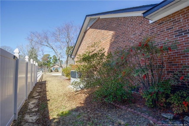 view of home's exterior featuring brick siding and fence