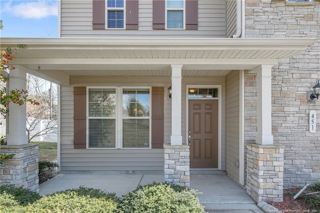 doorway to property featuring stone siding and a porch