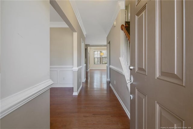 hallway featuring stairway, wood finished floors, wainscoting, crown molding, and a decorative wall