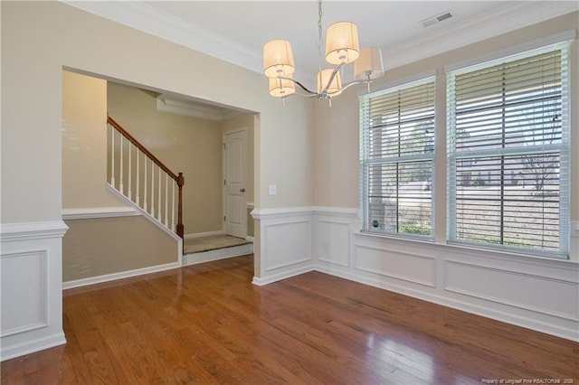 unfurnished dining area with visible vents, ornamental molding, wood finished floors, stairway, and a chandelier