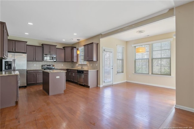 kitchen with backsplash, a center island, pendant lighting, appliances with stainless steel finishes, and dark wood-style floors