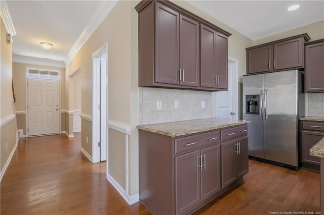 kitchen featuring light stone countertops, dark wood-type flooring, ornamental molding, and stainless steel fridge with ice dispenser