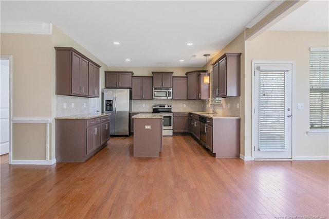 kitchen featuring tasteful backsplash, a kitchen island, appliances with stainless steel finishes, and wood finished floors