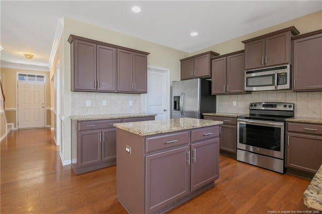 kitchen featuring backsplash, appliances with stainless steel finishes, a center island, and wood finished floors