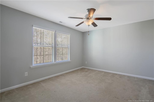 empty room with carpet, a ceiling fan, visible vents, and baseboards