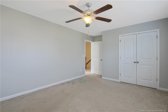 unfurnished bedroom with a ceiling fan, light colored carpet, baseboards, and a closet