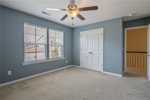 unfurnished bedroom featuring visible vents, a closet, carpet, baseboards, and ceiling fan