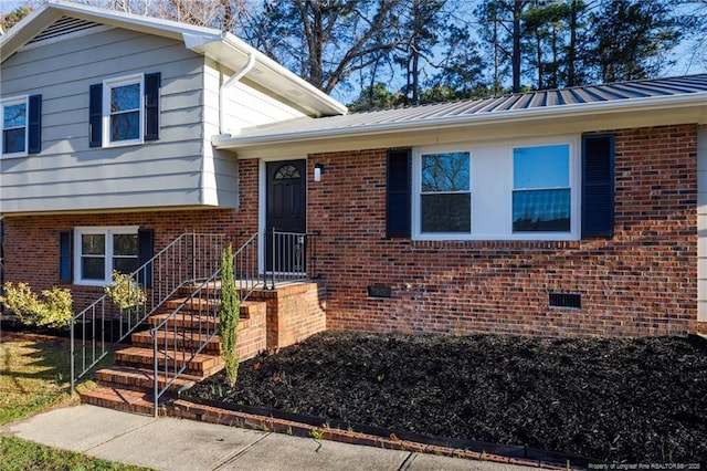 tri-level home with brick siding and metal roof