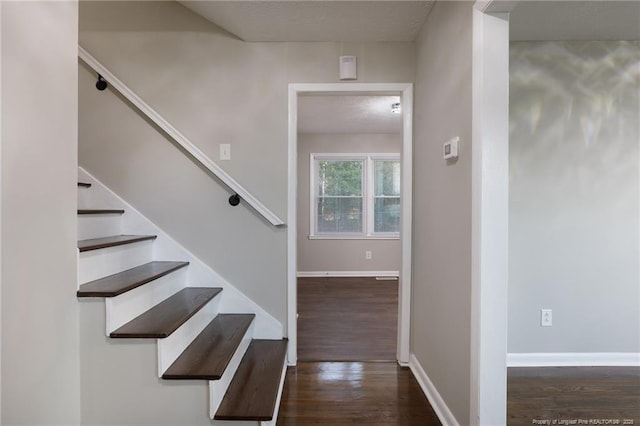 stairway featuring a textured ceiling, baseboards, and wood finished floors