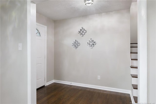 spare room featuring a textured ceiling, baseboards, and dark wood-style flooring