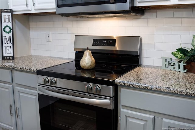 kitchen featuring decorative backsplash, white cabinets, light stone counters, and appliances with stainless steel finishes