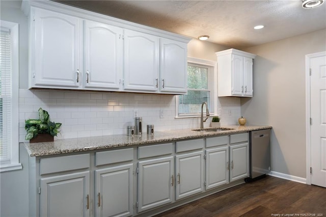 kitchen featuring a sink, tasteful backsplash, stainless steel dishwasher, white cabinets, and dark wood-style flooring