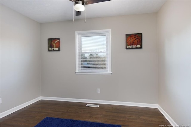 unfurnished room with visible vents, baseboards, dark wood-type flooring, and a ceiling fan