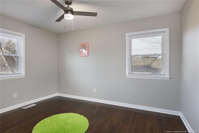 spare room featuring a ceiling fan, baseboards, visible vents, and dark wood-style flooring