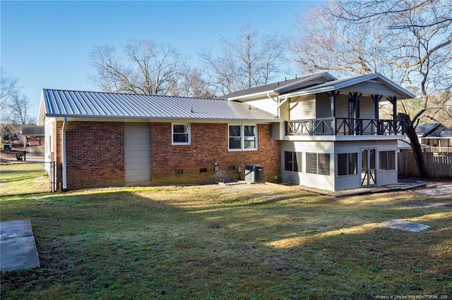 rear view of house with a balcony, fence, brick siding, and a lawn