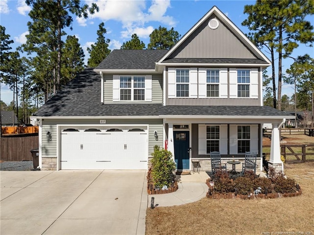 traditional-style house featuring roof with shingles, covered porch, driveway, and fence