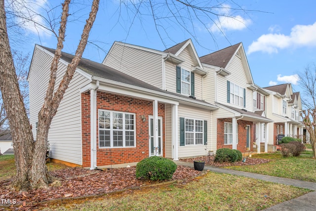 view of front of home featuring a residential view, brick siding, and a front yard