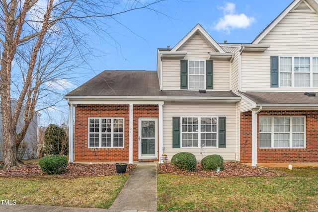 traditional-style house with a front lawn, brick siding, and a shingled roof