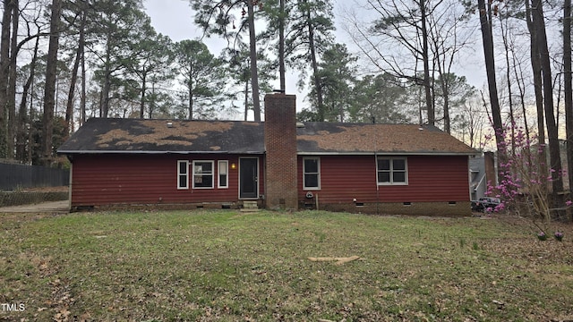 rear view of house featuring fence, roof with shingles, a yard, a chimney, and crawl space