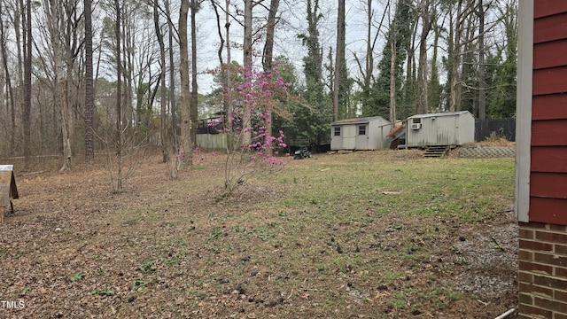 view of yard featuring a storage shed, an outbuilding, and fence