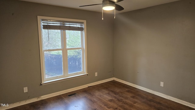 spare room featuring visible vents, ceiling fan, baseboards, and dark wood-style flooring